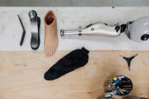 Composants d'une prothèse de jambe Ottobock Trias (pied carbone, genou, coque) et outils d'assemblage sur un établi de technicien.