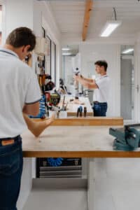 Prothésiste ajustant une jambe artificielle (prothèse transtibiale) sur un établi d'atelier. Outils, lumière vive et environnement propre.